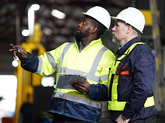 Two men wearing safety vests and hard hats inspecting a job site