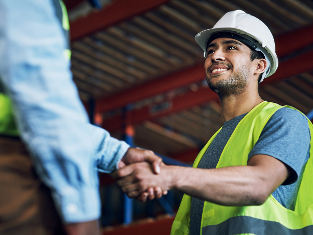 Two men shaking hands while wearing safety equipment