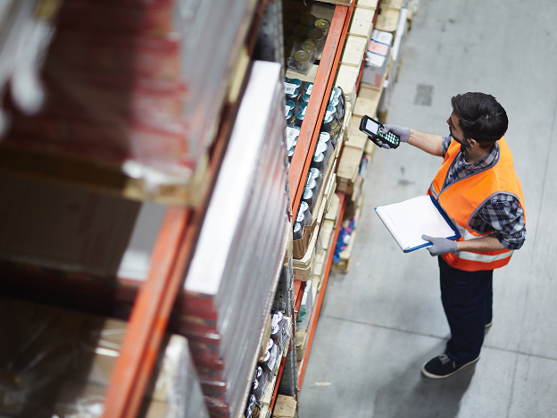A man wearing a safety vest scanning equipment in a warehouse