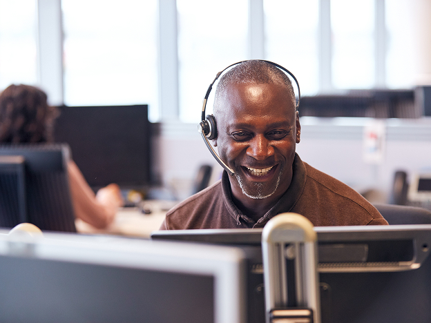 A man wearing a headset smiling while on the phone