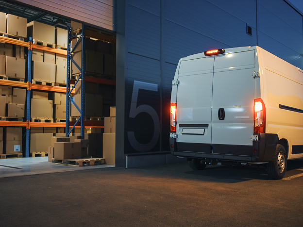 A truck backing up in front of a warehouse