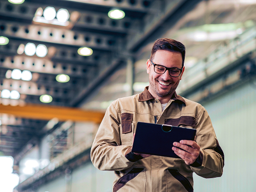 A man in a warehouse looking at a clipboard