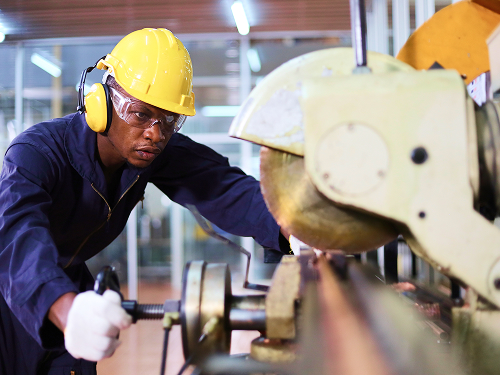 A man in a hard hat and googles using a cutting tool
