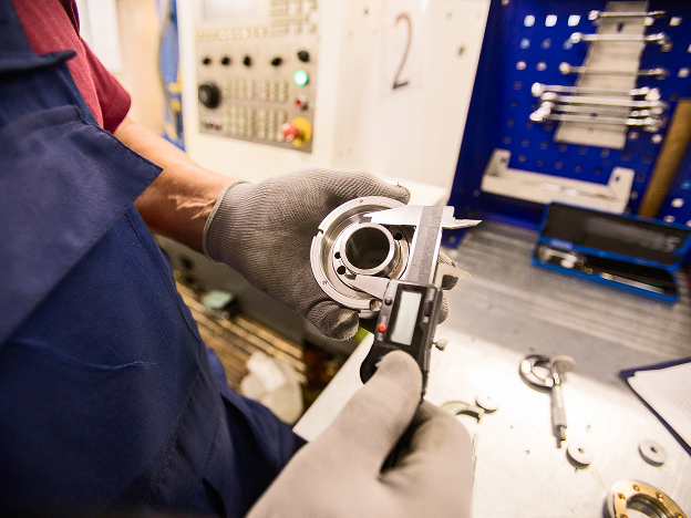 A man wearing gloves inspecting a tool